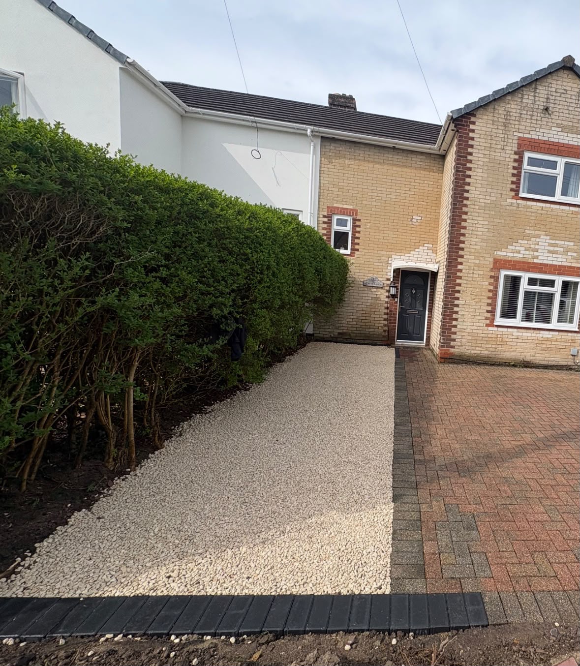 Cream decorative gravel side strip with black block paving edging alongside a block paved driveway