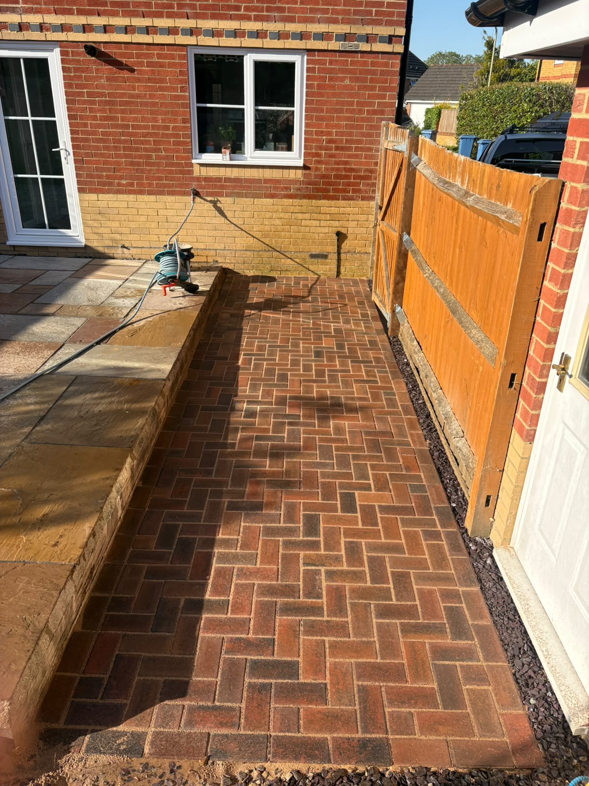 Block paving side driveway with black kerb edging beside a shrub border