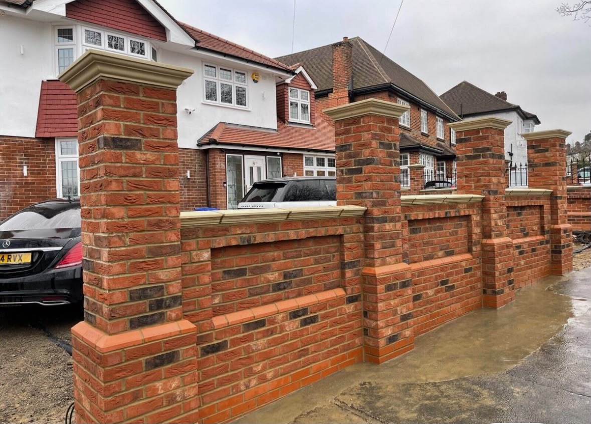 Solid red brick front garden wall with piers and sandstone copings