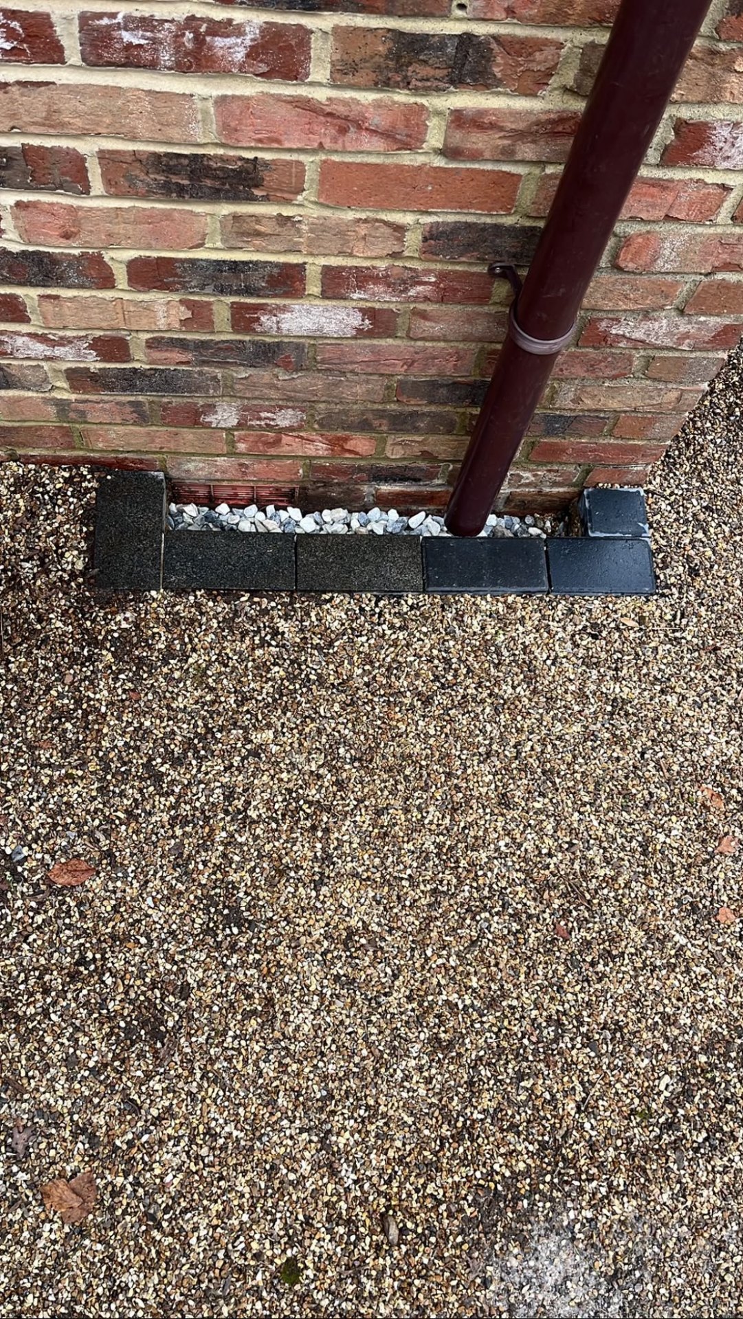Gravel driveway with brick weep vent and drainage detail against the wall