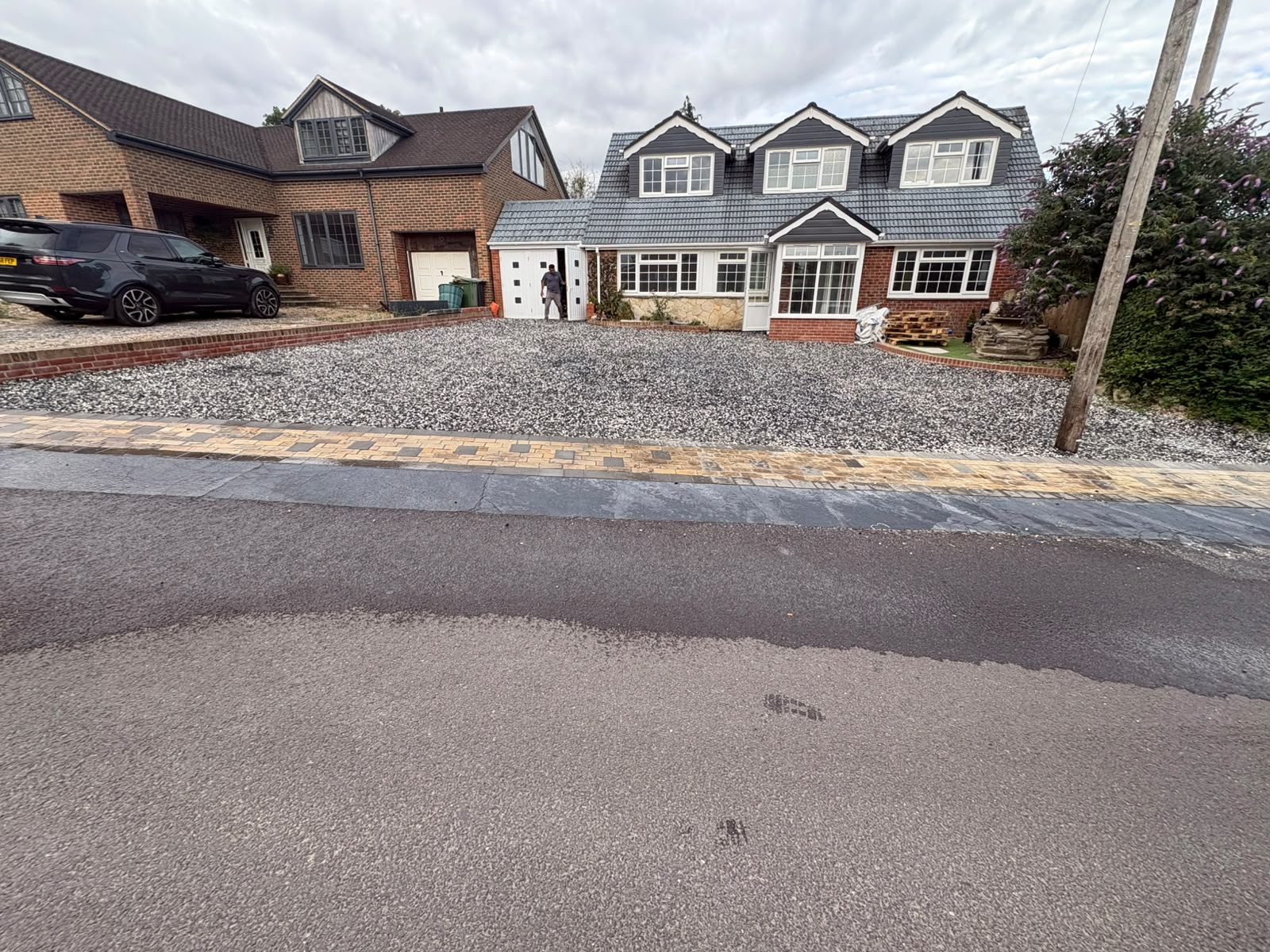 Pale limestone gravel driveway with a block paving apron in front of a house