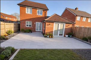 Light grey porcelain patio behind a new build home with planted borders