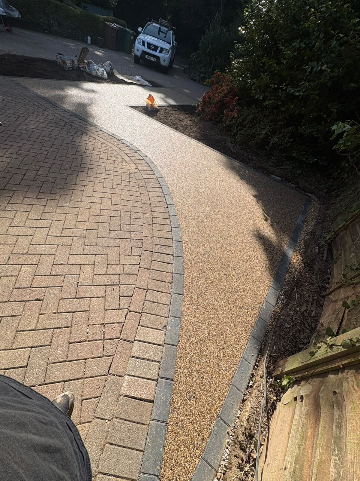 Golden resin bound driveway curving alongside a block paved area