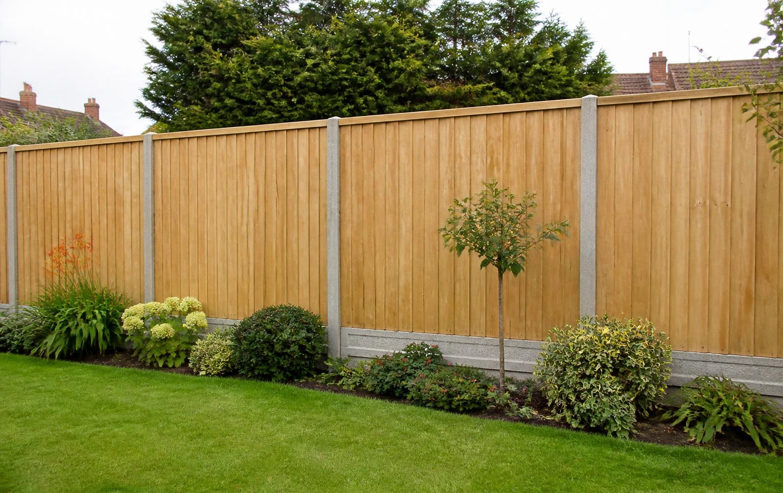 Newly installed close-board timber garden fence with concrete posts and gravel boards